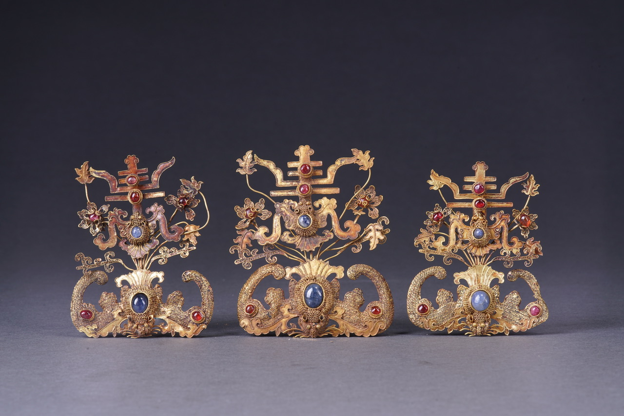 Ornements en forme de chauve-souris surmontée du caractère shou Dynastie Ming (1368-1644) Filigrane d'or ajouré et serti de rubis et saphirs Xi’an, musée des Beaux-Arts de Qujiang, XYB0043/1-3 © Peter Viem Kwok’s Dong Bo Zhai Collection (Collected in Xi’an Qujiang Museum of Fine Arts)